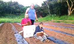 Class I participant Micah Buchanan with parents Moku and Laurie Buchanan planting strawberry plants.